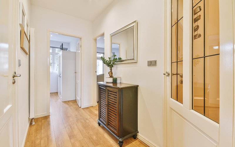 Dark wooden entryway shoe cabinet placed in a home hallway.